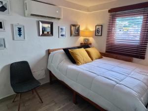 a bedroom with a bed and a chair and a window at Le Petit Bonheur - Peaceful Rooftop - 3 min Beach in Puerto Vallarta