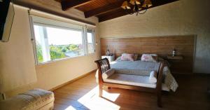 a bedroom with a bed with a window and a chair at Retiro de Las Cañas in Fray Bentos