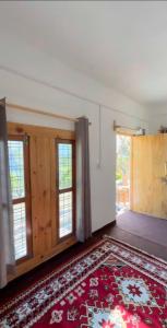 a room with a red rug on the floor and windows at Nivriti Stays in Nainital +3 photos