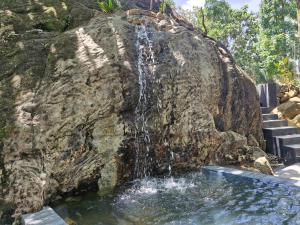 a waterfall in front of a large rock at Dhunhill Garden in Avissawella
