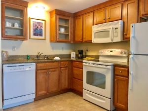 a kitchen with a stove, refrigerator, sink and dishwasher at White River Inn & Suites in White River Junction
