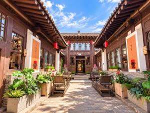 a courtyard of a building with chairs and plants at Elsewhere Hotel Inn Ancient City Center Branch in Pingyao