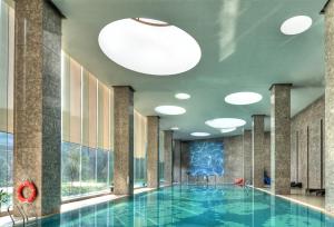 a swimming pool in a hotel with a large ceiling at Crowne Plaza Shanghai Anting-20 Minutes drive to National Exhibition and Convention Center & 15 Minutes drive to F1 in Jiading