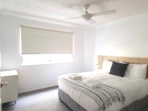 a bedroom with a bed with a ceiling fan at Pandanus Shores Kings Beach in Caloundra +16 photos