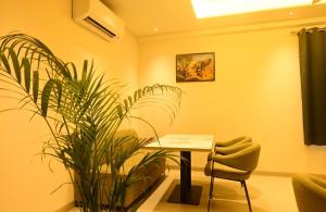 a room with a table and two plants and a chair at Hotel Layover Stay-3 Minutes From the Airport in Jaipur +3 photos