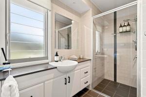 a white bathroom with a sink and a shower at Coast Bliss on Currambene in Huskisson +16 photos