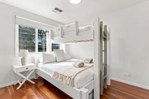 a white bedroom with a bunk bed and a window at Coast Bliss on Currambene in Huskisson