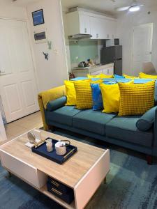 a living room with a couch with yellow and blue pillows at Bienvenida Condotel in Dumaguete