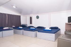a room with four blue beds and a tv at EnPensionne Hotel in Iloilo City +14 photos