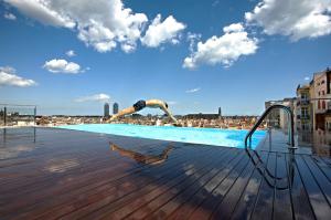 バルセロナにあるGrand Hotel Central, Small Luxury Hotelsの屋上のスイミングプールに飛び込む男