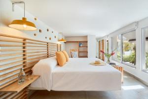 a bedroom with a large white bed and windows at Hotel Casa de sal in Acapulco