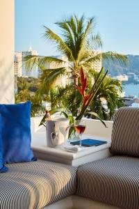a table with a glass of wine and a palm tree at Hotel Casa de sal in Acapulco
