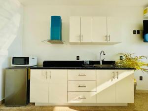 a kitchen with white cabinets and a sink and a refrigerator at Studio RoofTop with amazing view in Mahahual