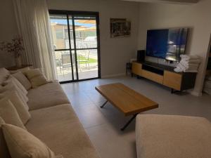 a living room with a couch and a flat screen tv at סוויטות שריתא in Shomera