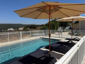a pool with two umbrellas and chairs and a swimming pool at סוויטות שריתא in Shomera