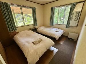 two beds in a room with two windows at KaKaJillJill in Hakuba