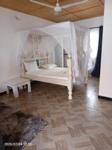 a white bed with a canopy in a room at Havilla Cecilia in Watamu