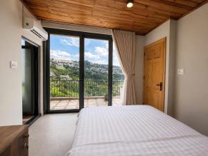 a bedroom with a bed and a large window at An Valley Villa Đà Lạt in Da Lat
