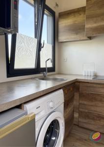 a kitchen with a washing machine and a sink at Studio Belle Place in Le Gosier