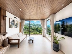 a living room with a couch and a large window at An Valley Villa Đà Lạt in Da Lat
