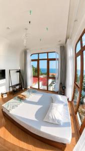 a large white bed in a room with windows at Coco Bay Hon Son in Lai Sơn