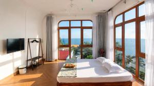 a bedroom with a large bed and large windows at Coco Bay Hon Son in Lai Sơn