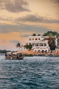 a boat in the water in front of a building at Lamu Treasures Shela Kenya in Shela