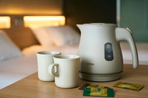 a coffee maker and two cups on a table at Karaksa Hotel Osaka Namba in Osaka