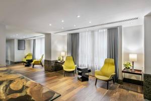 a waiting room with yellow chairs and a table at Meliá Paulista in São Paulo