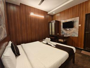a hotel room with a bed and a tv at Arunik Inn in Pondicherry