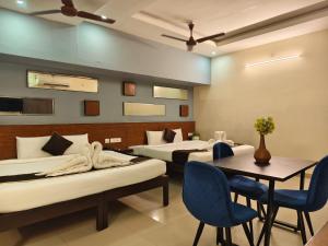a room with three beds and a table and chairs at Arunik Inn in Pondicherry