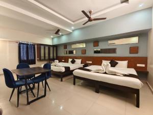 a hotel room with two beds and a table and chairs at Arunik Inn in Pondicherry
