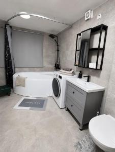 a bathroom with a tub and a sink and a washing machine at SMART flat - Ranna 49 in Sillamäe +14 photos