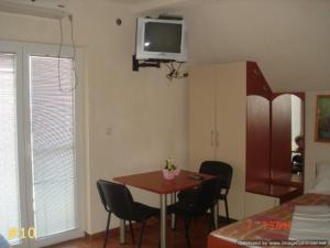 Habitación con mesa, sillas y TV en la pared. en Apartments Dan Dar en Nov Dojran