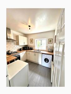 a kitchen with white cabinets and a washer and dryer at 13a Avon road in Worcester