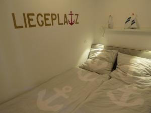 an unmade bed in a room with a sign on the wall at App "Ahoi" Familie Köhn in Schönberger Strand +5 photos