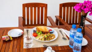 a wooden table with a plate of food and water bottles at Dhiffushi Reef & Beach in Dhiffushi +21 photos