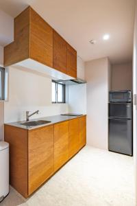 a kitchen with wooden cabinets and a sink and a refrigerator at 9STAY Kikukawa in Tokyo