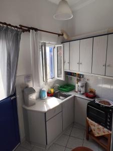 a kitchen with white cabinets and a sink and a window at Michalis little sunrise in Mamádhos
