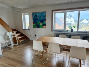 a dining room with a wooden table and white chairs at Charming Townhouse In Thyborøn in Thyborøn