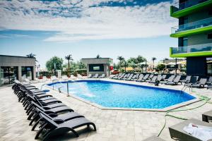 a swimming pool with lounge chairs next to a building at Apartament Alezzi Beach in Năvodari