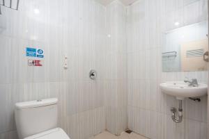 a white bathroom with a toilet and a sink at Ava Guesthouse Lampung in Tanjungkarang