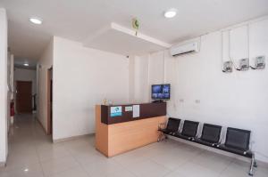a waiting room with chairs and a desk with a television at Ava Guesthouse Lampung in Tanjungkarang