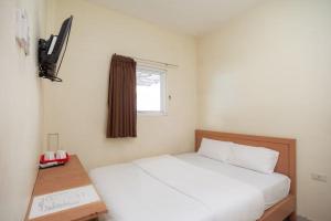 a bedroom with a white bed and a window at Ava Guesthouse Lampung in Tanjungkarang