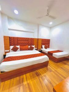 two beds in a room with wooden floors at Hotel Grand Royal Sandhu in Amritsar