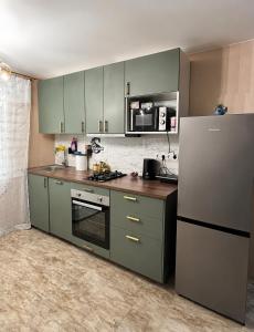 a kitchen with green cabinets and a refrigerator at SMART flat - Ranna 49 in Sillamäe