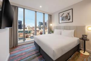 a hotel room with a bed and a large window at Brady Hotels Elizabeth Street in Melbourne