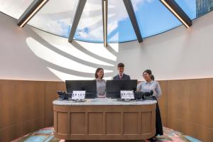 a group of three people standing at a table with laptops at Brady Hotels Elizabeth Street in Melbourne