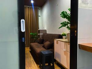 a living room with a brown couch and a stool at Tropical Aurora Tetebatu in Tetebatu
