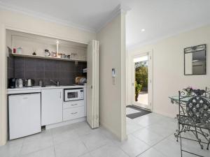 a kitchen with white cabinets and a table and a window at Via Bella Vista in Wangaratta